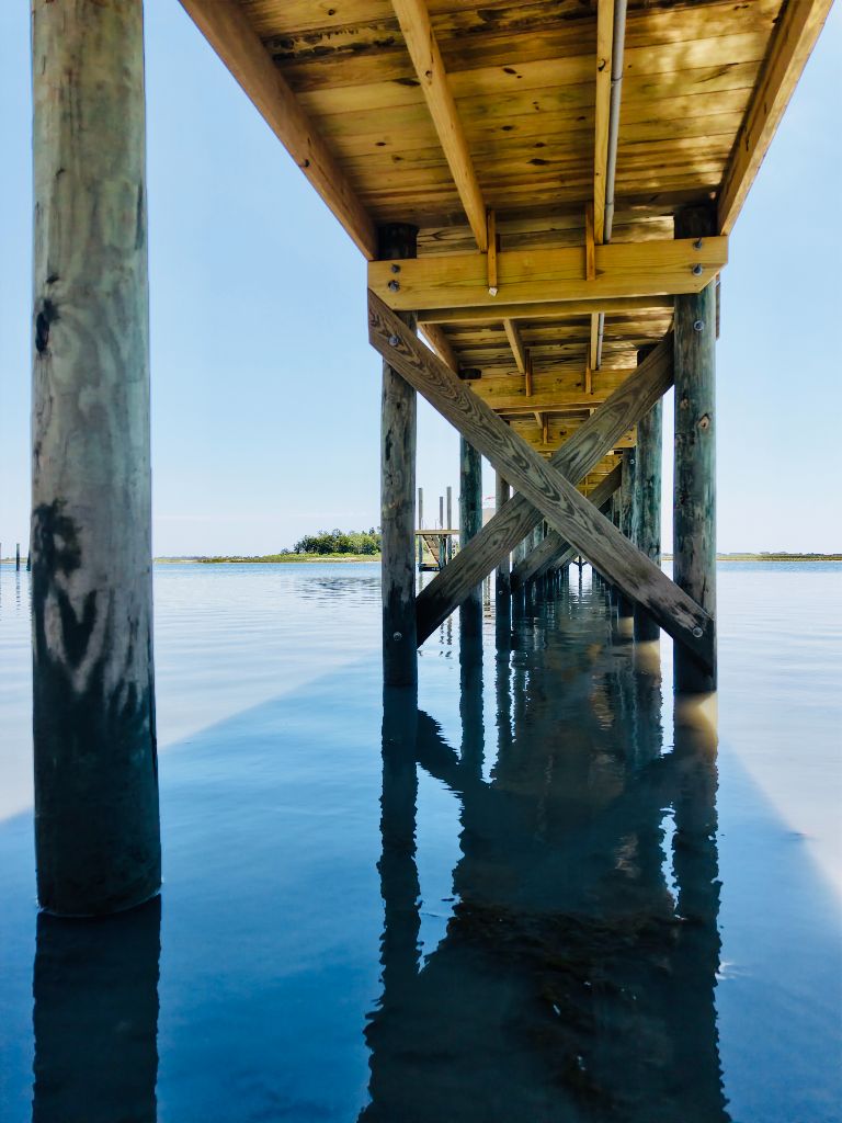 Under-dock view showing pressure-treated pilings and X-bracing construction