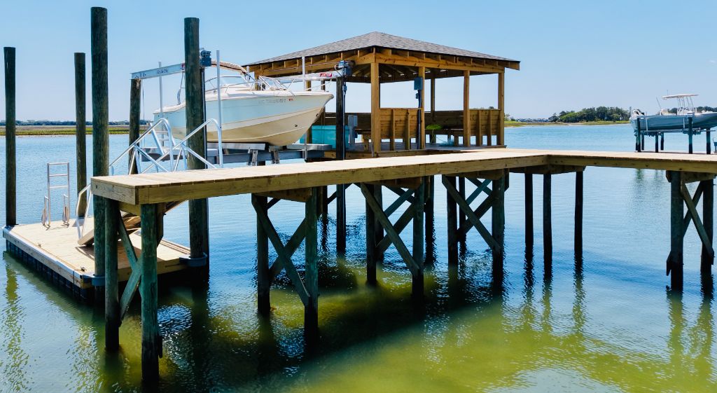 Wide view of dock with boathouse, boat on lift, and long walkway
