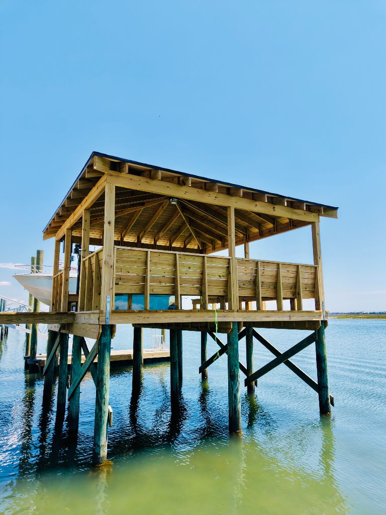 Large open-frame boathouse with pressure-treated lumber construction over water